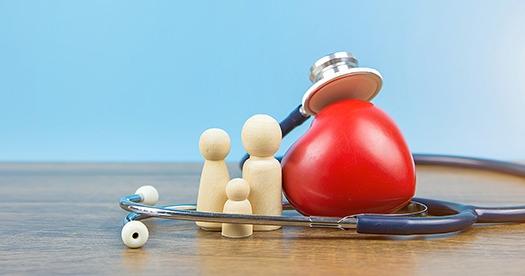 photo of stethoscope around a toy heart and wooden people